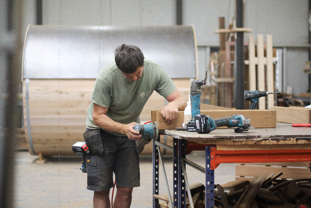 Een vakman bewerkt hout voor een buitensauna